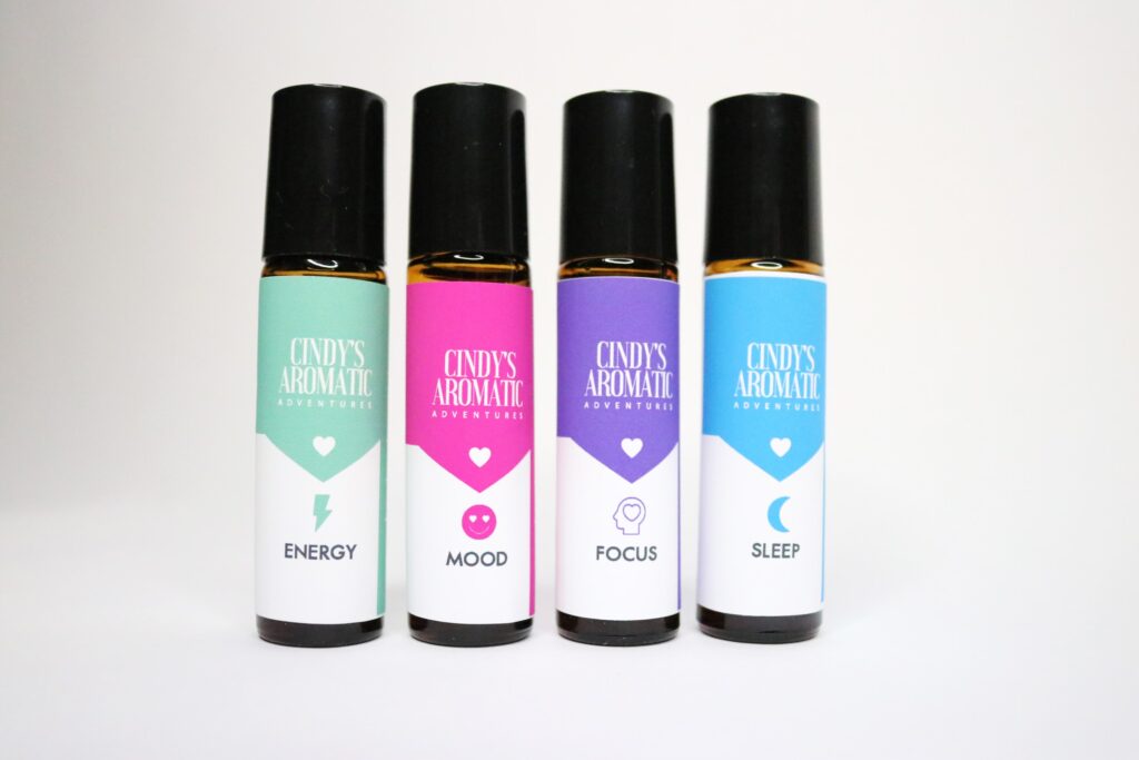 four different scented roller bottles on a white canvas.