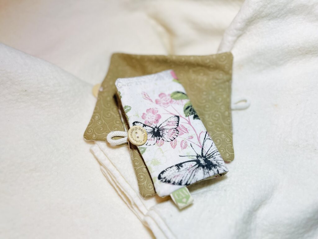 white and pink butterfly with rose baby seat belt cover on a white blanket.