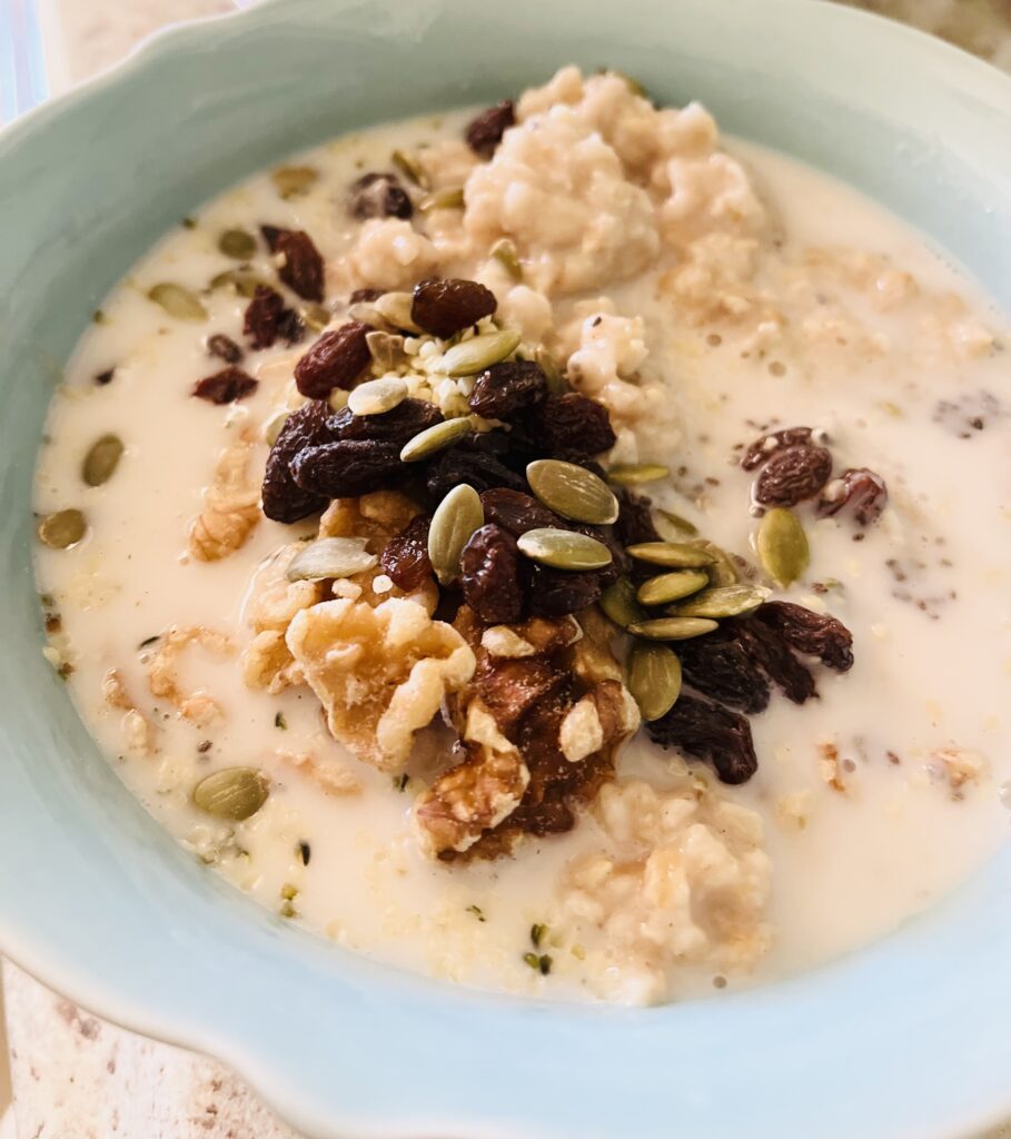 Oatmeal breakfast bowl served with almond milk and topped with raisins and seeds