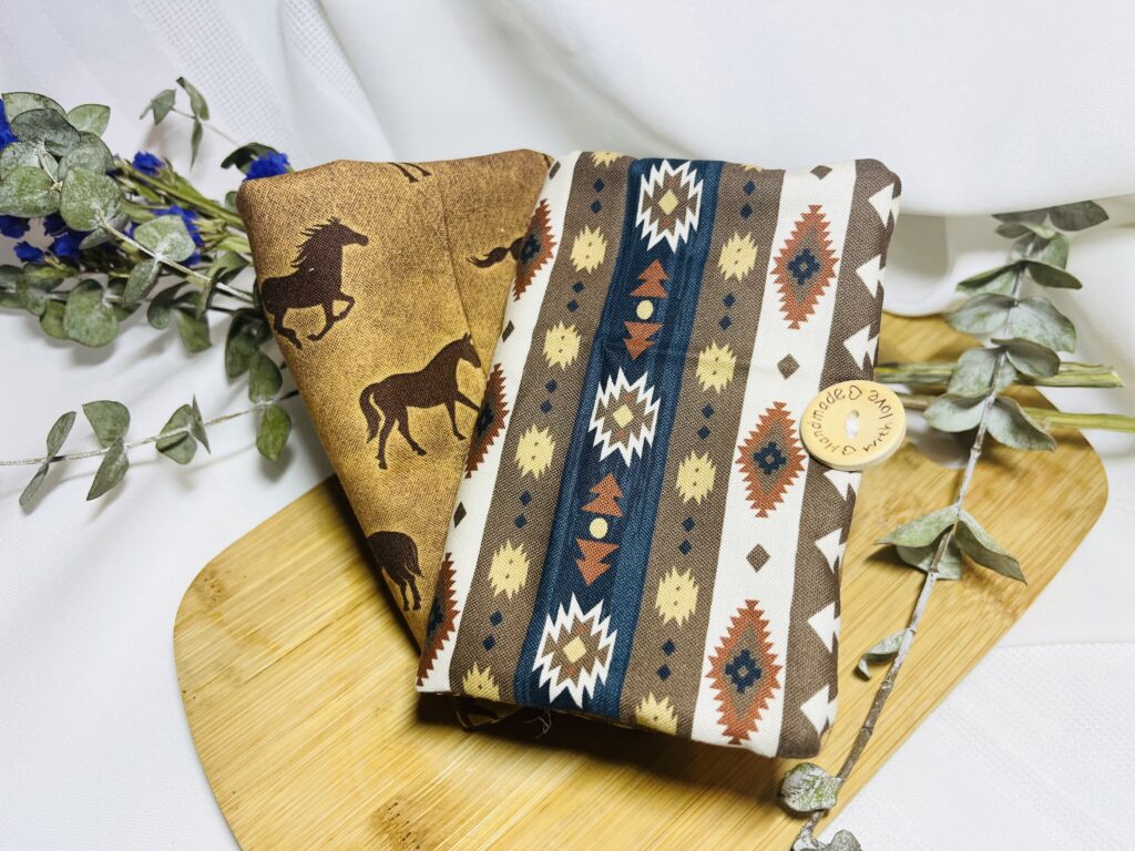 Cowboy themed handmade baby seat belt cover on a cutting board with leaves and a white background