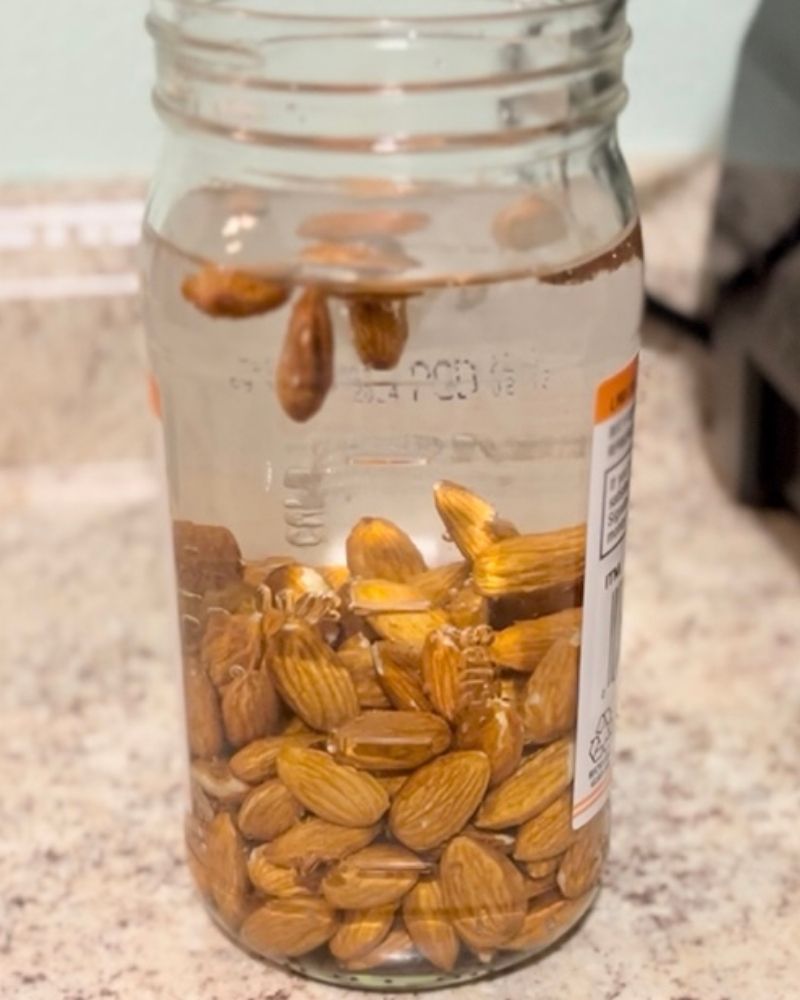 Almonds being soaked in water in a glass container