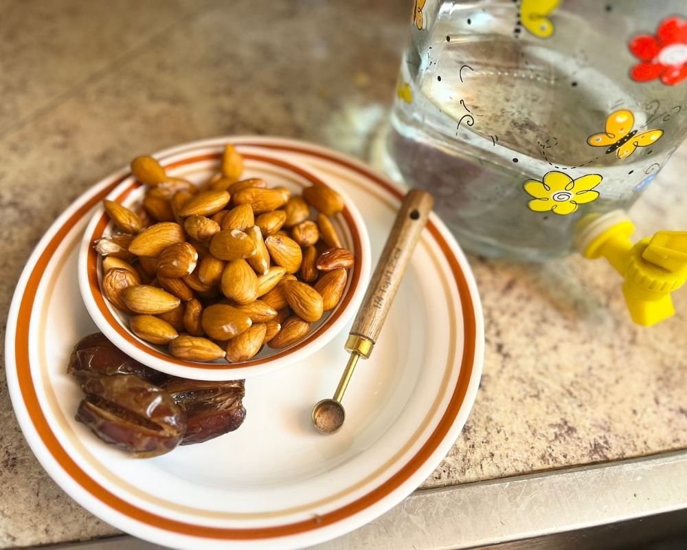 On a plate you have the ingredients to make almond milk, almonds, dates, salt and water on the side.