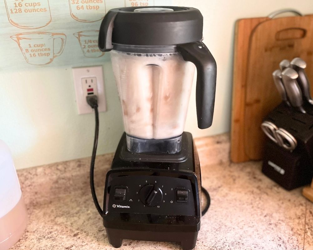 Blending almonds in a blender on a counter top to make almond milk.