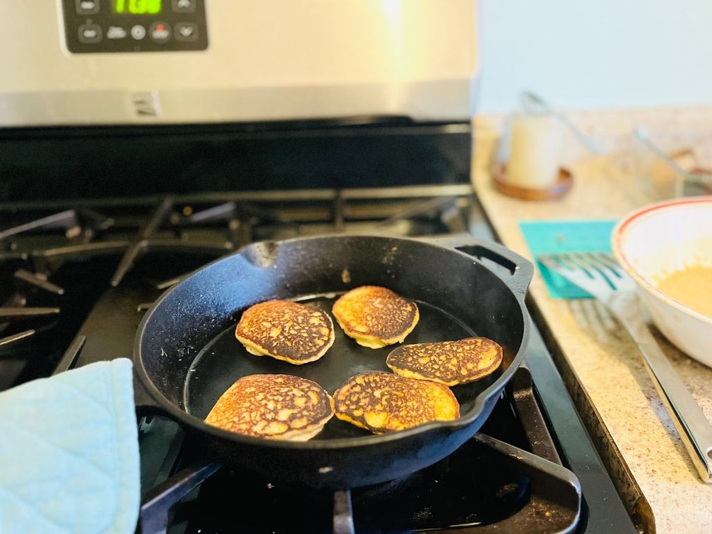 cast iron skillet with 5 golden brown mini pancakes.