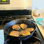 cast iron skillet with 5 golden brown mini pancakes.