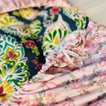 Blue floral cushion wrapped with a pink floral cover with a white ribbon tide to it.