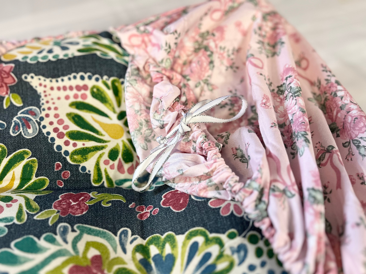 blue colorful cushion wrapped in a pink floral cover with a ribbon tied in a bow.