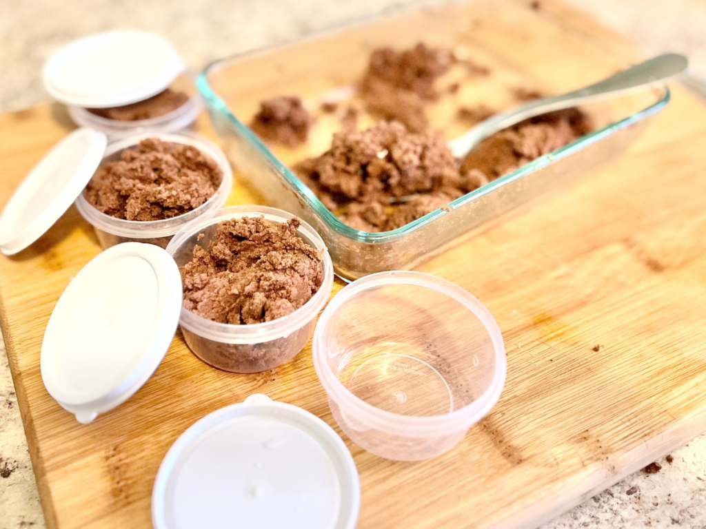 small containers with white lid filled with chocolate and a bigger glass container next to them with a silver spoon.