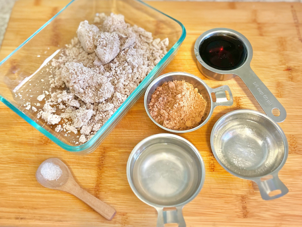displayed ingredients inside containers on a wooden cutting board.